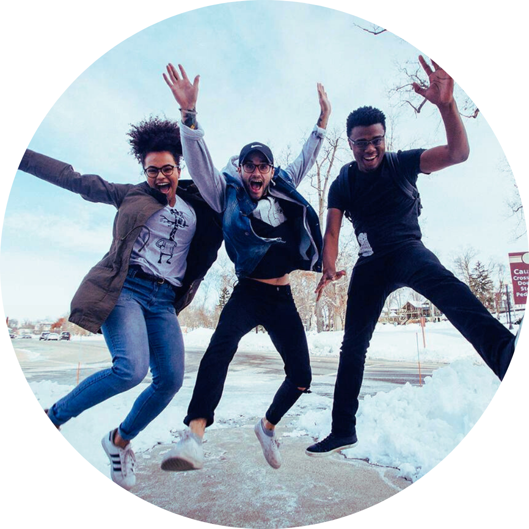 A woman and two men jumping excitedly in front of snow