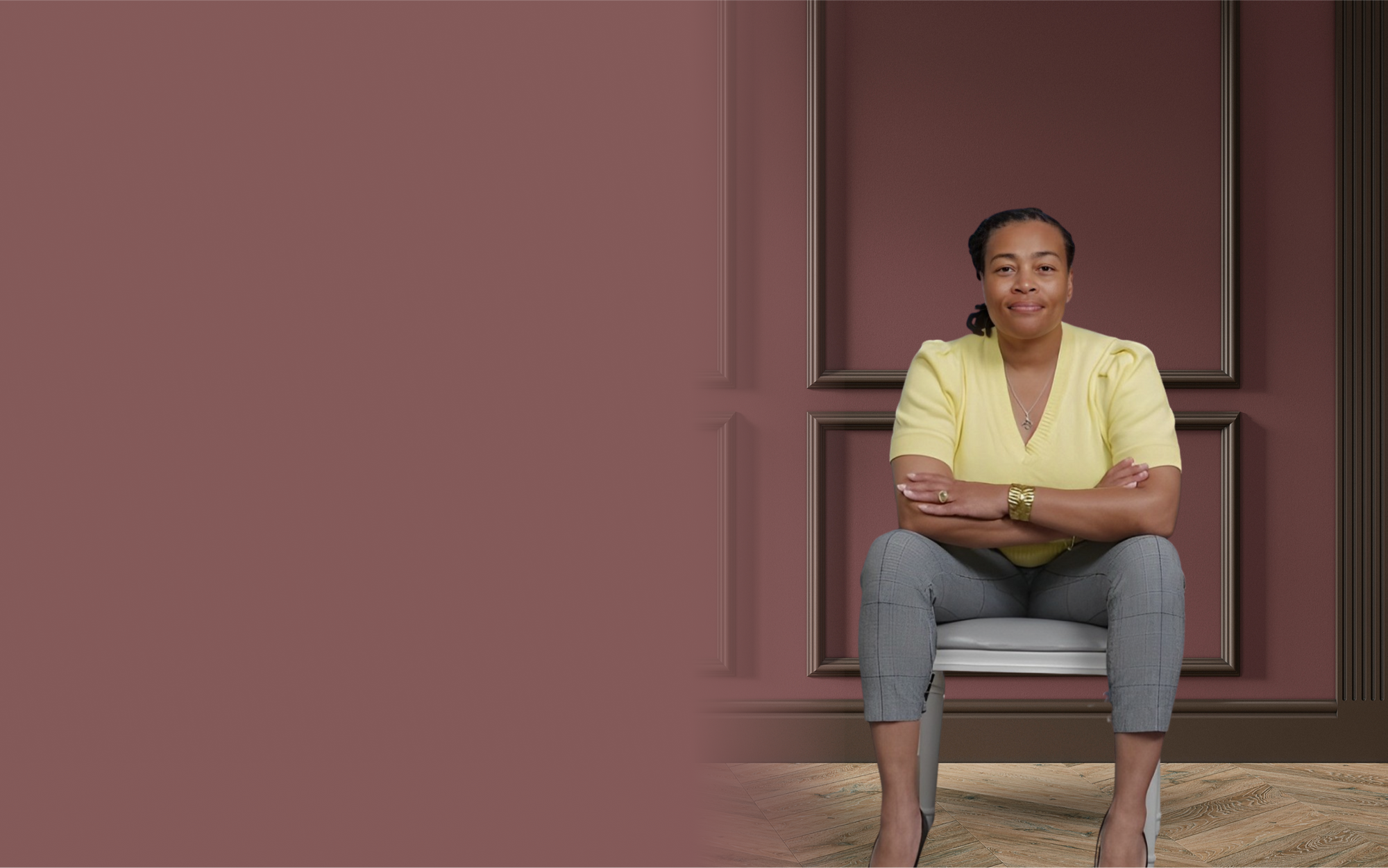 Dr. Andrea Peters sitting on a chair in front of a dark rose wall with crown moulding