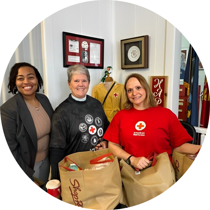 Dr. Andrea Peters stands with two women from the American Red Cross, all smiling at the camera after filling relief bags