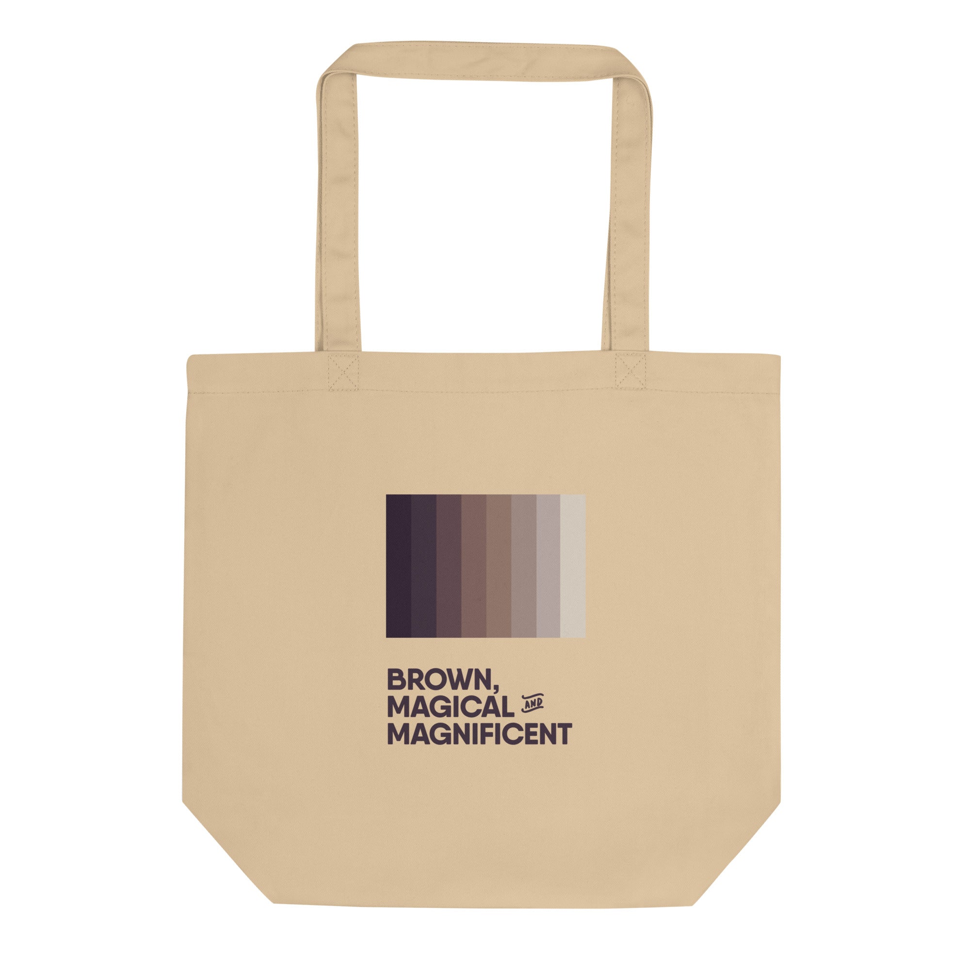 A oyster-colored canvas tote bag with sturdy handles. The words "Brown, Magical, and Magnificent" are printed in various shades of brown, creating a gradient effect.