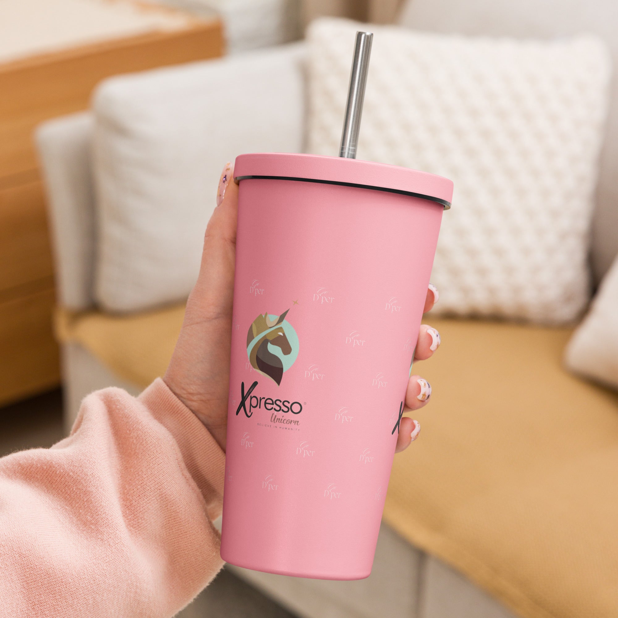 A hand holding a pink Xpresso Unicorn tumbler with a straw, ready for a refreshing drink.