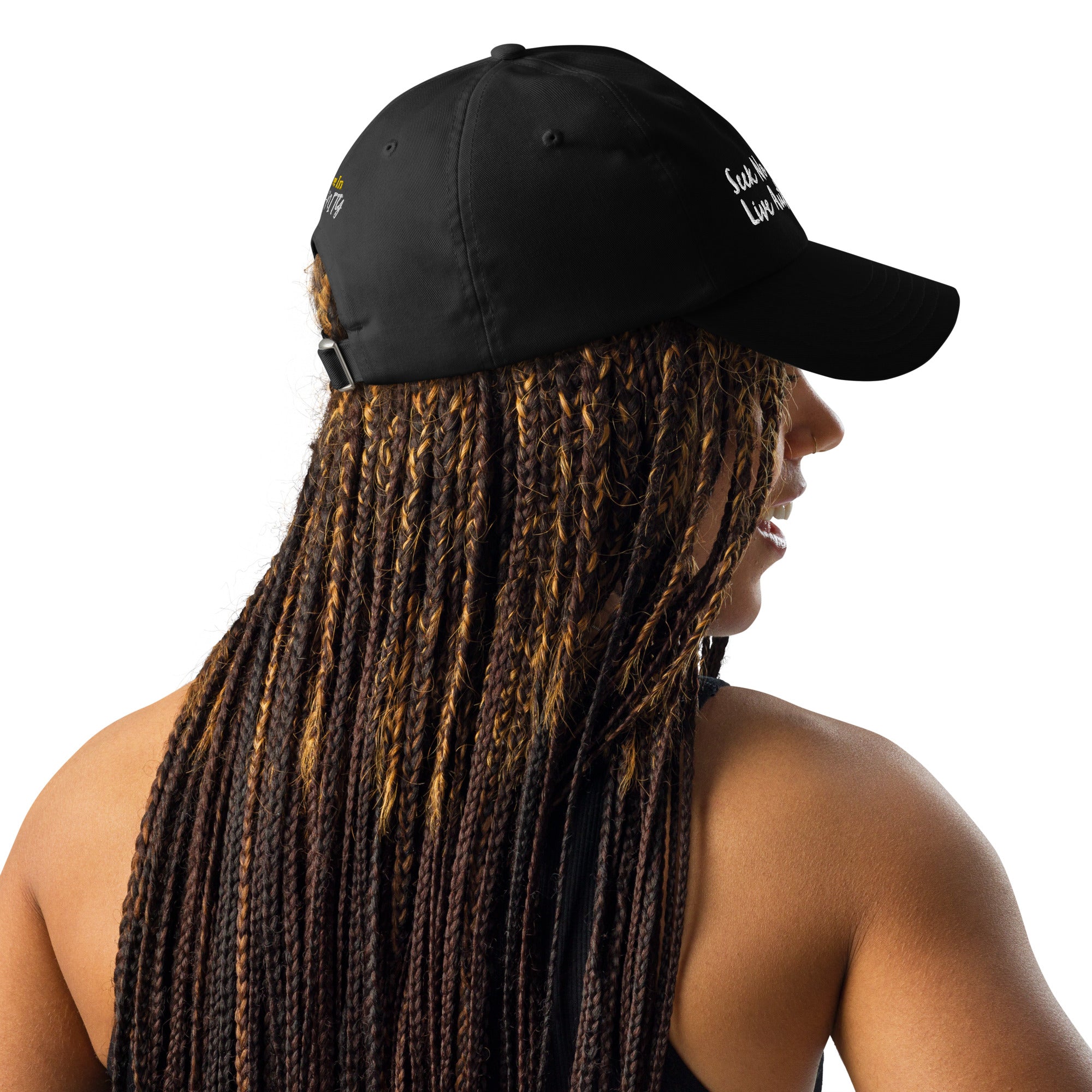 A Black woman with stylish braids looking sporty in a black Under Armour hat.