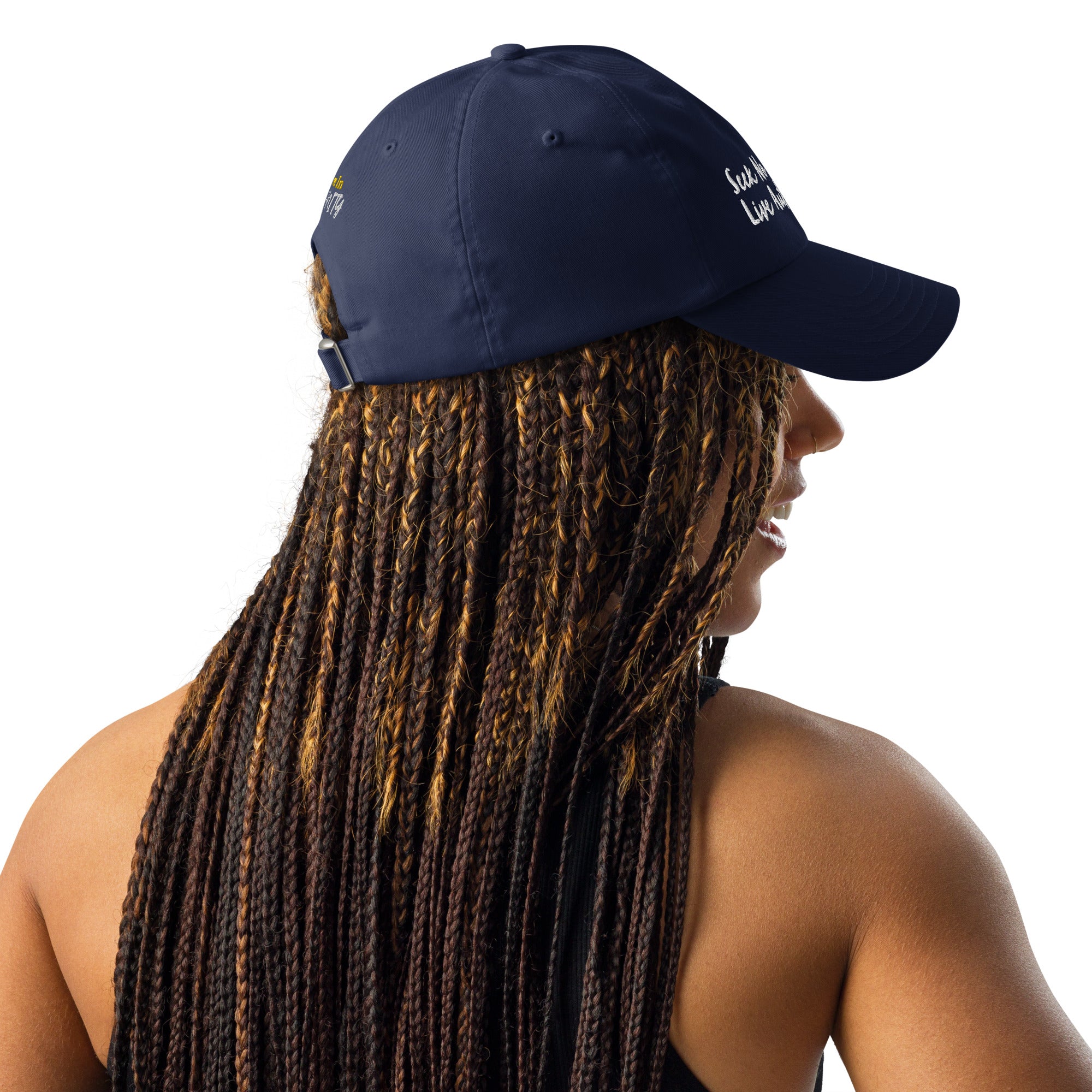 A gray Under Armour hat worn by a Black woman with braids, showcasing the hat's versatility and style.