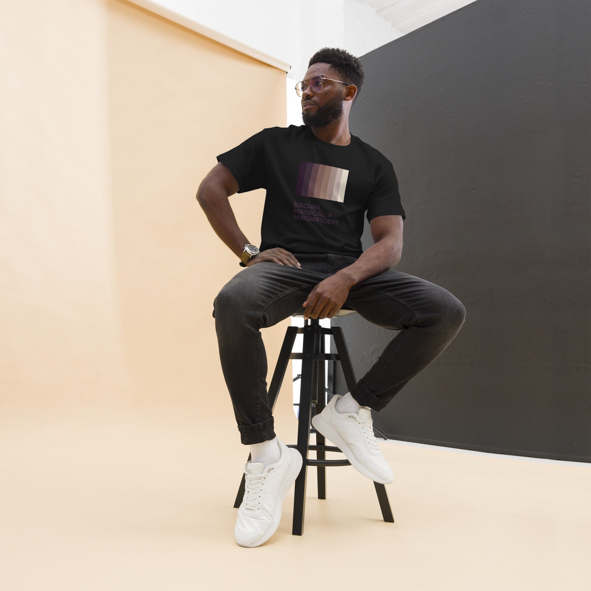 A Black man wearing a black shirt with a brown color gradient and the text "Brown, Magical, and Magnificent.