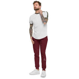 A man with tattoo sleeves showcasing a pair of comfortable, unisex maroon fleece sweatpants.