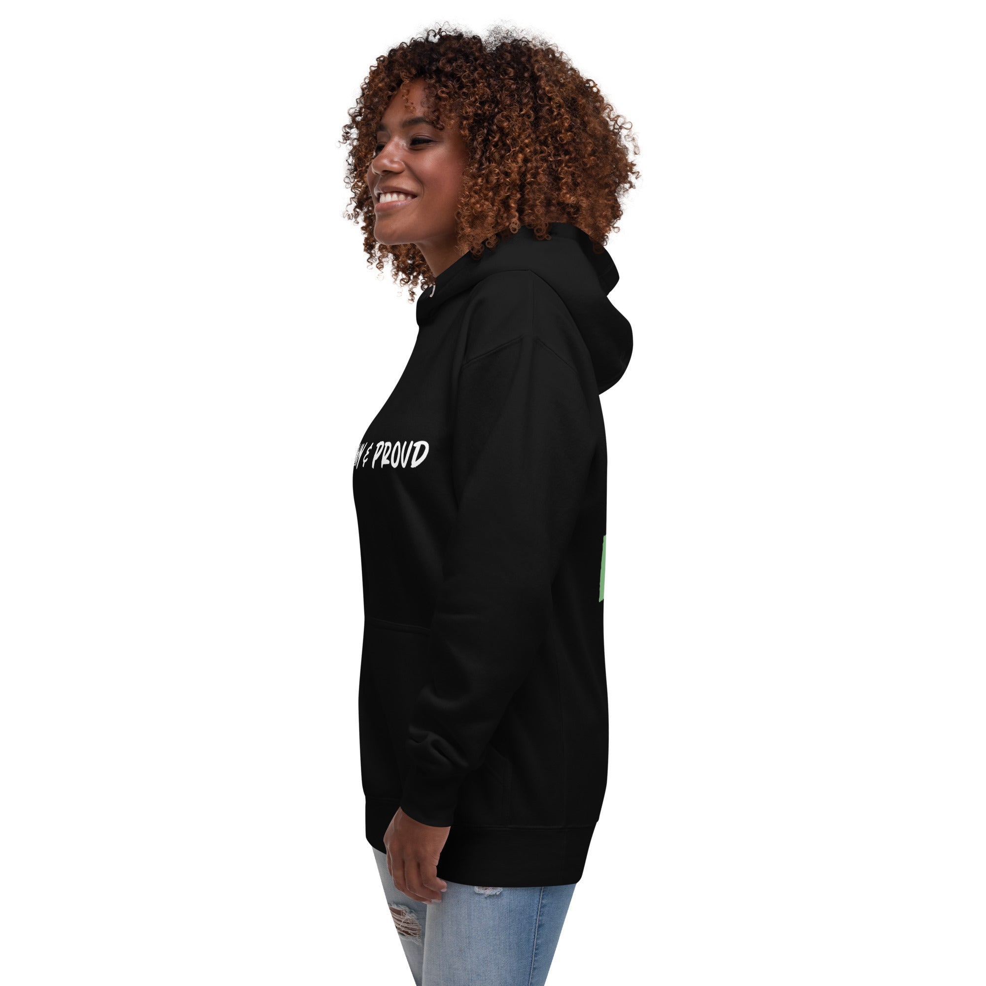 A radiant smile shines on a Black woman's face as she wears a navy blue hoodie proclaiming "Brown & Proud," capturing a moment of self-love and acceptance.