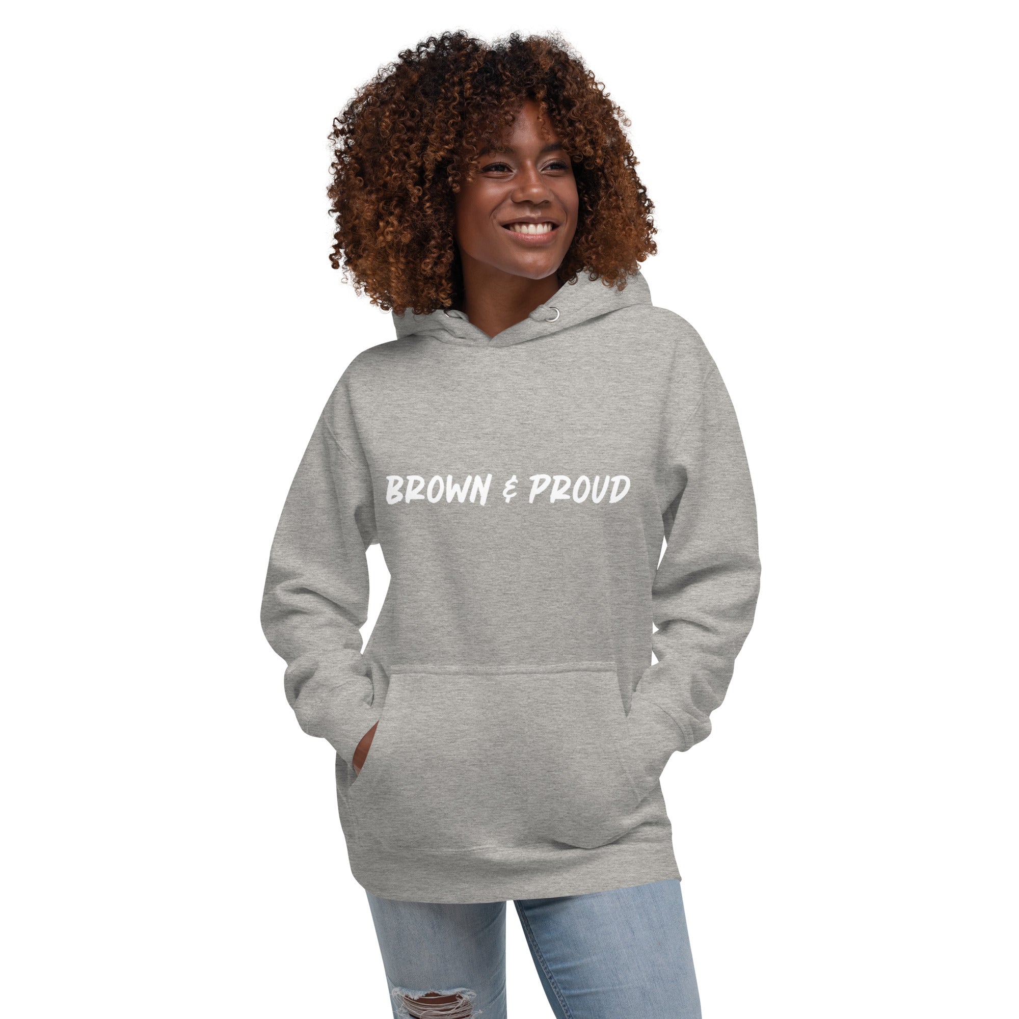 A Black woman beams with pride, wearing a gray hoodie that declares "Brown & Proud." The image exudes confidence and self-love.