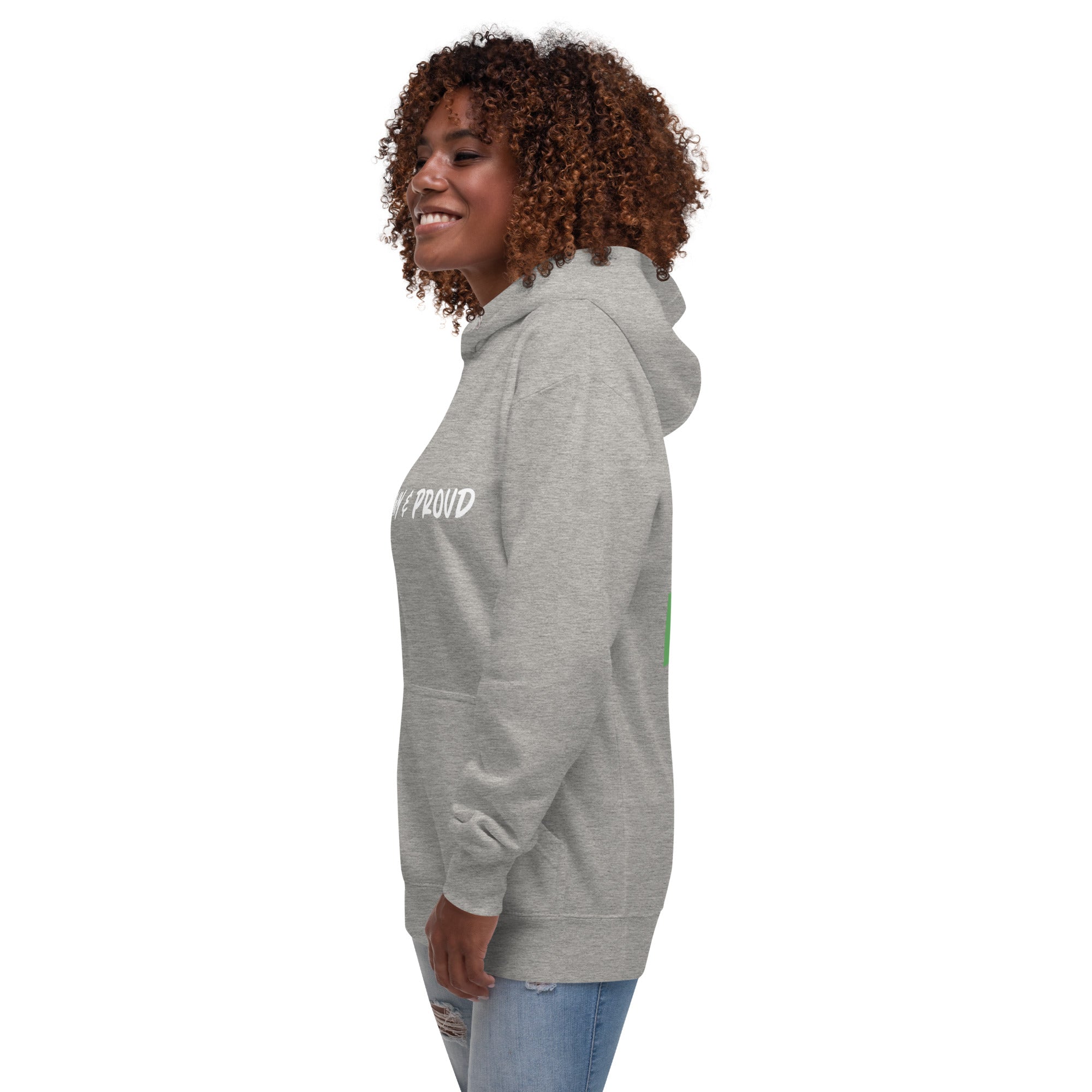 A Black woman smiles, sporting a gray hoodie with the words "Brown & Proud" printed boldly across the chest.