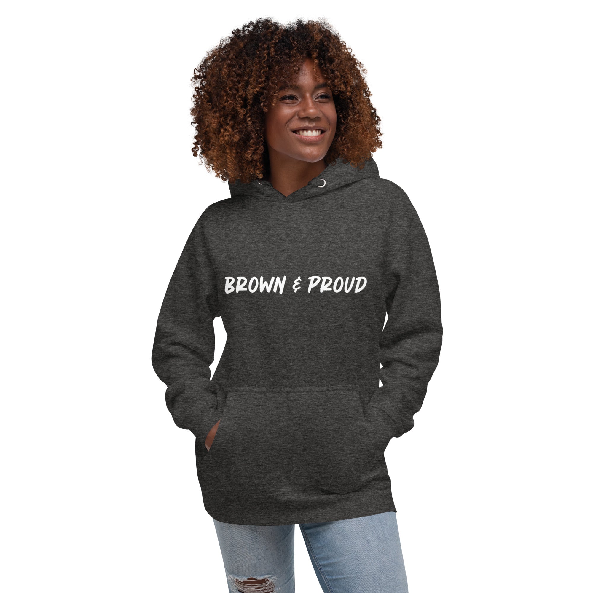 A radiant smile shines on a Black woman's face as she wears a charcoal hoodie proclaiming "Brown & Proud," capturing a moment of self-love and acceptance.