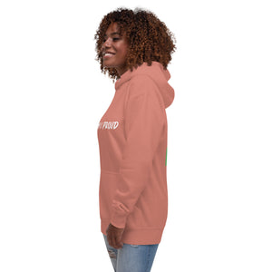 A Black woman smiles, sporting a dusty rose hoodie with the words "Brown & Proud" printed boldly across the chest