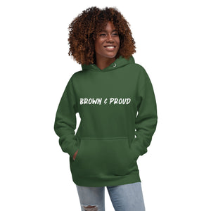 A radiant smile shines on a Black woman's face as she wears a forest green hoodie proclaiming "Brown & Proud," capturing a moment of self-love and acceptance.