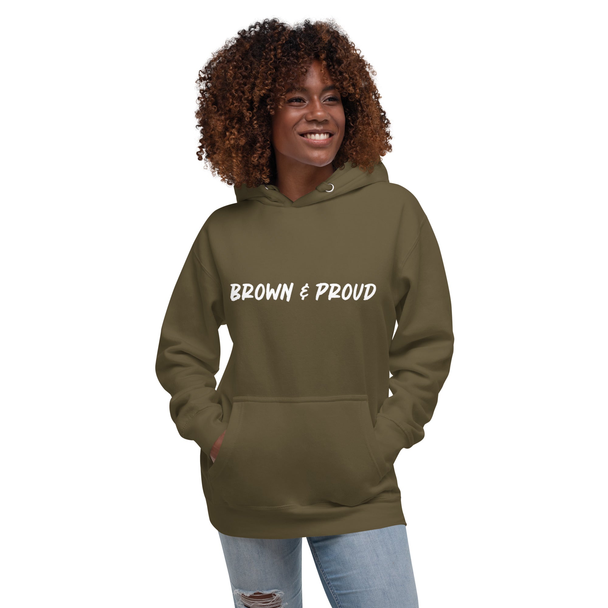 A radiant smile shines on a Black woman's face as she wears a military green hoodie proclaiming "Brown & Proud," capturing a moment of self-love and acceptance.