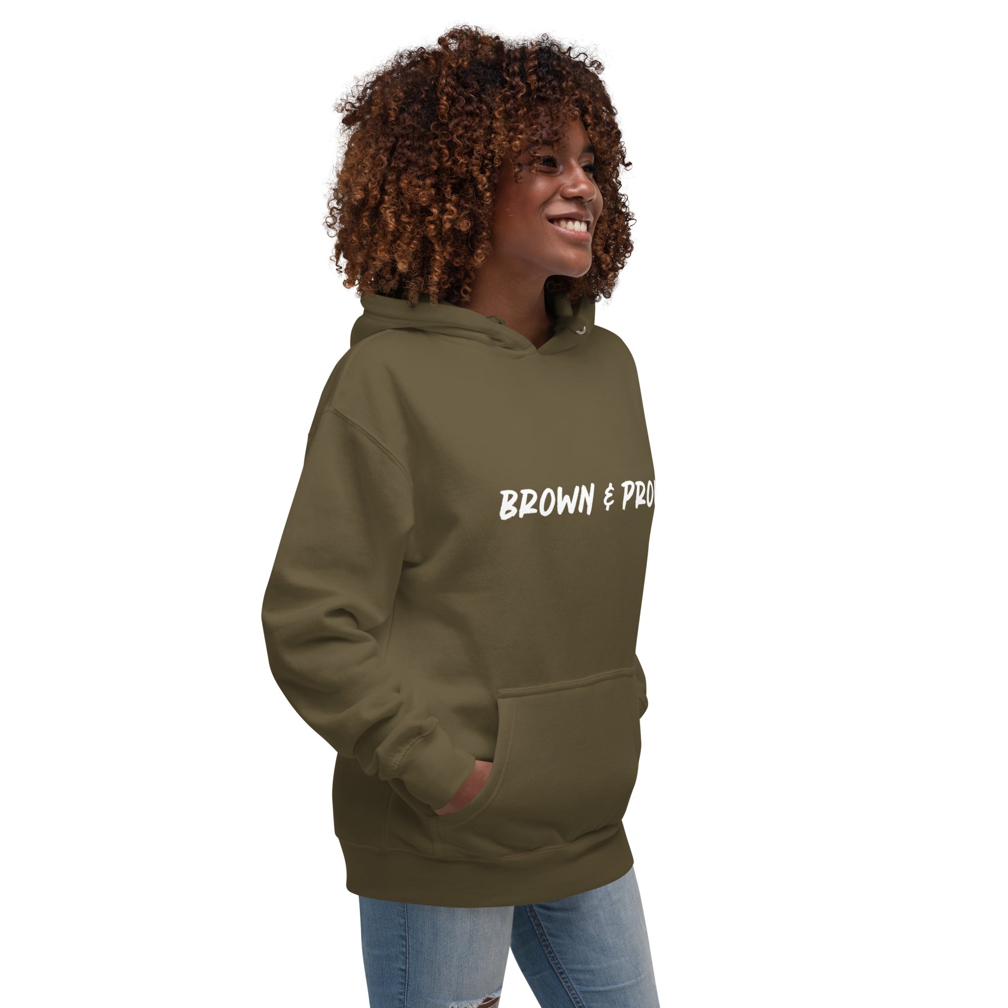 A Black woman exudes confidence, wearing a military green hoodie emblazoned with the phrase "Brown & Proud."